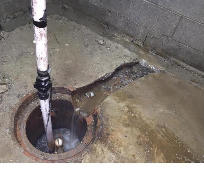 A sump pump inserted in a hole in a basement